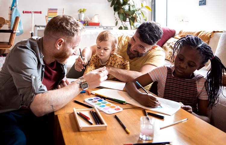 Two adults and two children sitting together at a coffee table having fun with coloring books